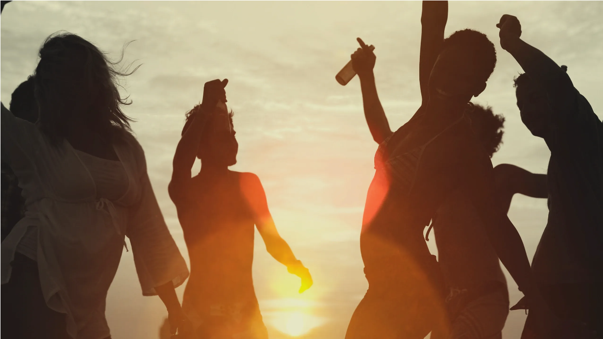 Friends dancing outdoors at sunset